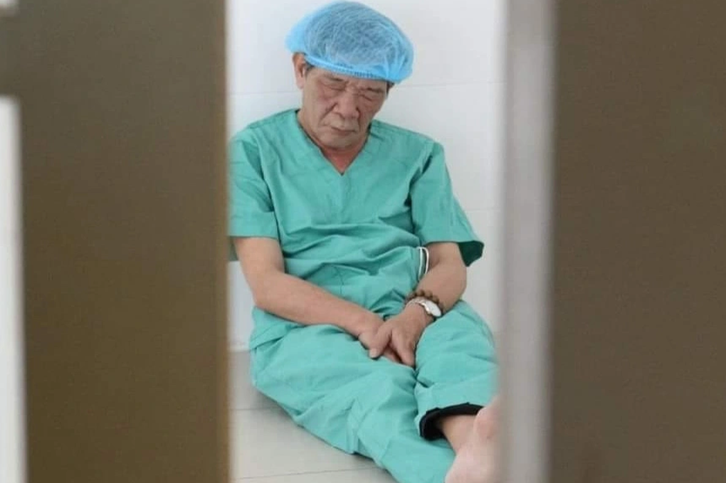Bác sĩ ngồi trên sàn nhà, lưng dựa tường chợp mắt sau phẫu thuật từ thiện - 1